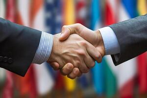 Two businessmen shaking hands in front of international flags photo