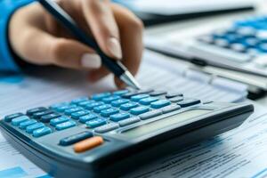 Accountant calculating tax using calculator and pen on desk photo