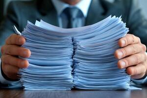 Businessman holding stack of documents at office desk photo