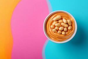 Creamy peanut butter with peanuts in a bowl on colorful background photo