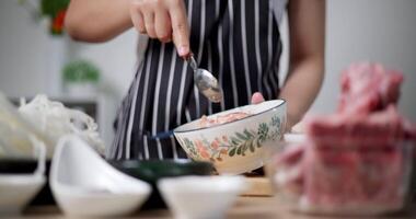 Selective focus shot, A young woman is mixing minced pork with various seasonings in a bowl. video