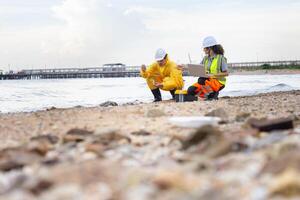 Environmental Engineers Conducting Field Work for Pollution Control, Engineers Analyzing Environmental Data on a Beach Cleanup Project, Workers Collecting Water Samples for Environmental Research photo