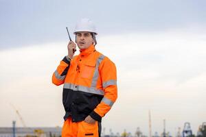 Port Worker Communicating via Walkie-Talkie, Industrial Supervisor with Two-Way Radio on Site, Engineer at Work with Communication Device photo