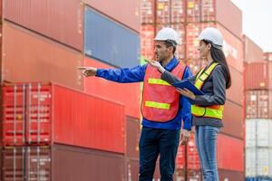Engineer and foreman worker team in hardhat and safety vest checking containers box from cargo, Engineers team with clipboard managing cargo operations, Teamwork concepts photo