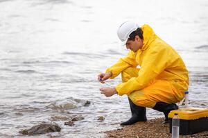 Environmental Scientist Testing Water Quality by a Lake, Man in Hazmat Suit Collecting Water Sample for Analysis, Ecologist Examining Water Purity in Natural Environment photo