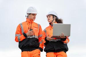 Industrial Engineers Collaborating at Port Terminal with Laptop and Walkie Talkie, Dock Worker in Safety Uniforms Working at Harbor Site photo
