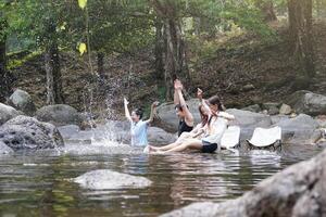 Group of Friends Having Fun in a Rocky Stream, Young Adults Relaxing and Playing in a Forest River, Friends Enjoying a Refreshing Day by the Stream in Nature photo