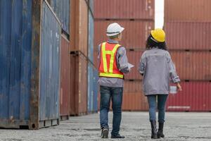 Engineer and foreman dock worker team in hardhat and safety vest checking containers box from cargo, Teamwork concepts photo