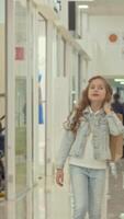 Joyful little girl carrying a shopping bag while exploring the vibrant mall video
