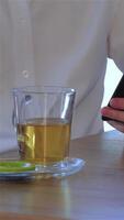 Close up of man enjoying tea while using smartphone video
