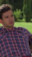 Charming male student relaxing on a sunny park bench video