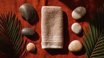 Beige Towel with Stones and Palm Leaves on Orange Background photo