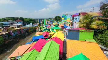 Cinematic FPV drone flythrough of rainbow-colored rooftops and river in vibrant village in Malang, Indonesia. Colorful houses, tropical atmosphere, and local life. video