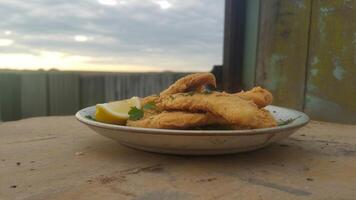 A bowl of fried fish with lemon wedges photo