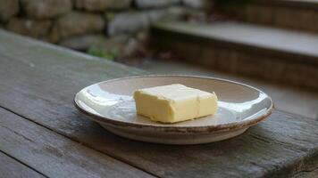 A piece of butter sits on a plate on a wooden table photo