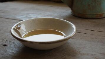 A bowl of water sits on a table next to a teapot photo