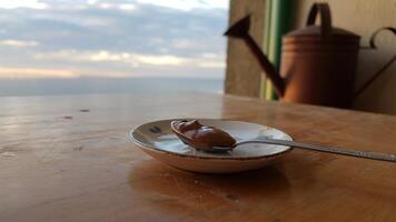 A spoon and a bowl of peanut butter on a table photo