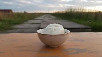 A bowl of ice cream sitting on a wooden table photo