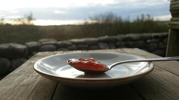A spoon and a bowl of jam on a table photo