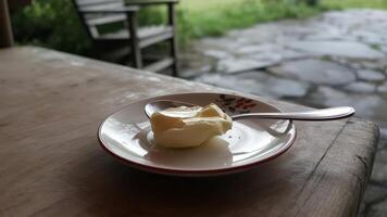 A spoon and a bowl of butter on a table photo