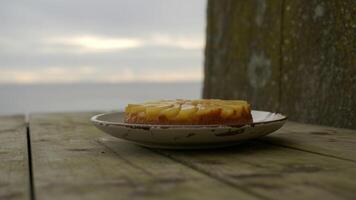 Pineapple upside down cake on a plate outdoors with a blurred ocean background on a cloudy day photo