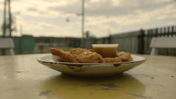 Plate of chicken tenders with dipping sauce on a yellow table outdoors on an overcast day view photo