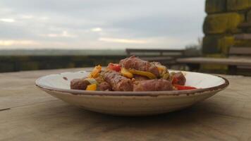 Close up of a plate of sausage and peppers on a wooden table with a blurred background view photo