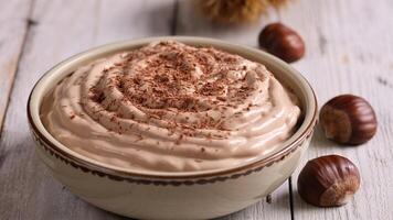 A bowl of chocolate mousse topped with chocolate shavings and chestnuts on a wooden surface photo