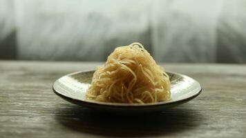 Close up of a plate of noodles with a blurred background on a wooden surface in a studio setting photo