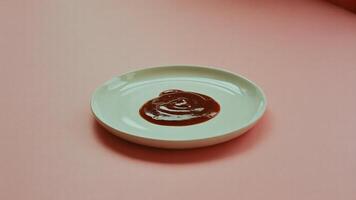 A small white plate with a dollop of ketchup on a pink surface in a minimalist setting studio shot photo
