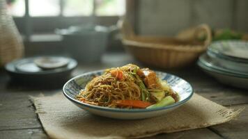 A plate of stir fried noodles with vegetables on a burlap cloth with dishes in the background photo