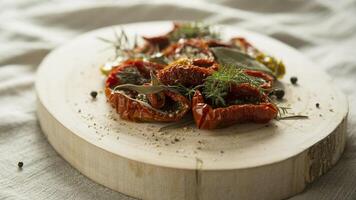 Close up of sun dried tomatoes with herbs and spices on a wooden board on a textured surface photo