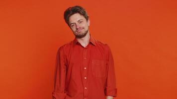 Dislike. Upset unhappy Caucasian man showing thumbs down sign gesture, expressing discontent, disapproval, dissatisfied negative feedback. Attractive bearded guy indoors isolated on orange background video