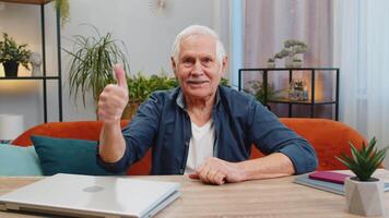 Like. Happy excited senior man looking approvingly at camera show thumbs up like sign positive something good great news, positive feedback at home indoors. Elderly mature grandfather sits at table video