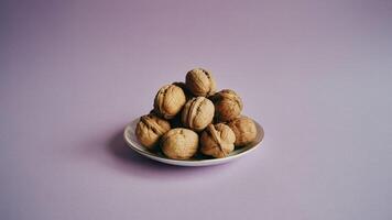 a sta ck of ca ra mel fudge pieces on a sma ll pla te a ga inst a light purple ba ckground in soft studio light photo