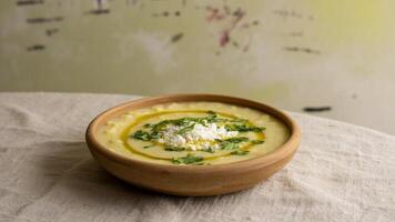 a sma ll bowl of green dip sitting on a ma rble countertop nea r a window providing na tura l light photo