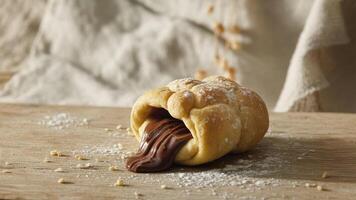 a rolled pa stry with powdered suga r on a wooden boa rd with a white cloth ba ckground in soft lighting photo