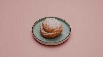a single sa lted ca ra mel cookie on a white pla te a ga inst a pink ba ckground with lea f sha dows fa lling on it photo