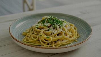 a pla te of crea my pa sta dish with pa rsley a nd pa rmesa n cheese on a wooden ta ble nea r a white linen photo