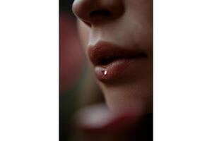 Close up of a person's face with a water droplet on their lower lip in focus view photo