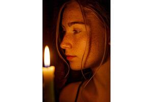 Portrait of a woman illuminated by candlelight in a dimly lit environment photo