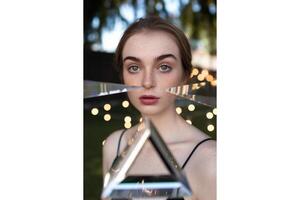 Portrait of a woman holding a prism in front of her face with bokeh background photo