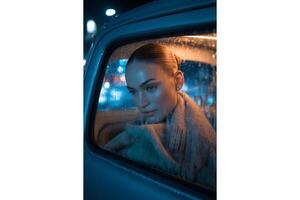 Portrait of a woman in a car on a rainy night looking out the window at the city photo