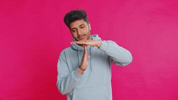 Tired serious upset Indian young man showing time out gesture, limit or stop sign, no pressure, I need more time, take a break, relax, rest, help. Arabian guy isolated on pink studio background video