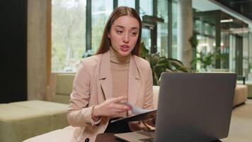 Angry young lady boss arguing over call using laptop while sitting at modern workplace in the office. Unsatisfied woman manager shows diagram and tells subordinates about the company's problems. video