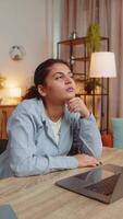 Young Indian woman freelancer prepares startup project for presentation finds idea. Hispanic girl think success sitting with laptop computer at home office desk. Remote distant working. Vertical. video