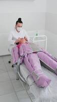 Beautician therapist making pressotherapy procedure treatment. Hardware cosmetology technique used in fight against puffiness, cellulite. Affects lymphatic system with compressed air supplied in suit video