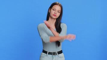 Young woman say No hold palm folded crossed hands in stop gesture, warning of finish, prohibited access, declining communication, body language, danger. Girl on blue background. People lifestyles video