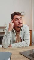 Smart focused man freelancer guy pensive thoughtful sitting at table home office sitting with laptop thinks about solving problem with online service app makes decision deep in thoughts. Vertical video