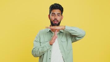 Tired serious upset Indian young man showing time out gesture, limit or stop sign, no pressure, I need more time, take a break, relax, rest, help. Arabian guy isolated on yellow studio background video